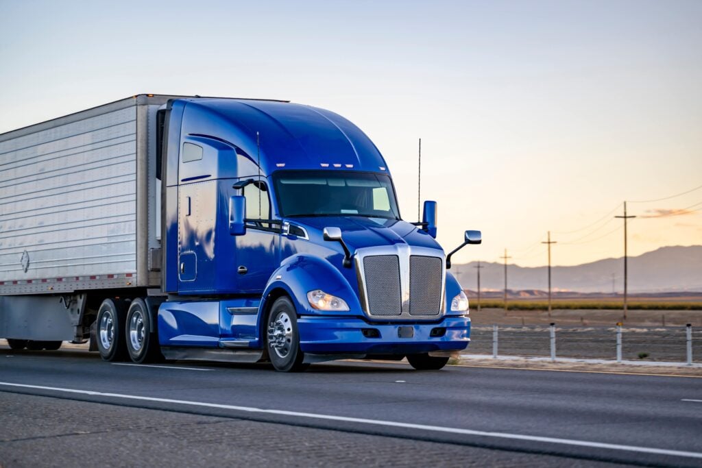 Enclosed blue truck transporting cars