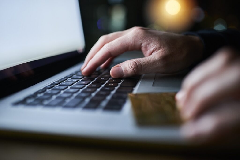 Person typing on a laptop while holding a credit card – tips for buying a car on Edmunds.