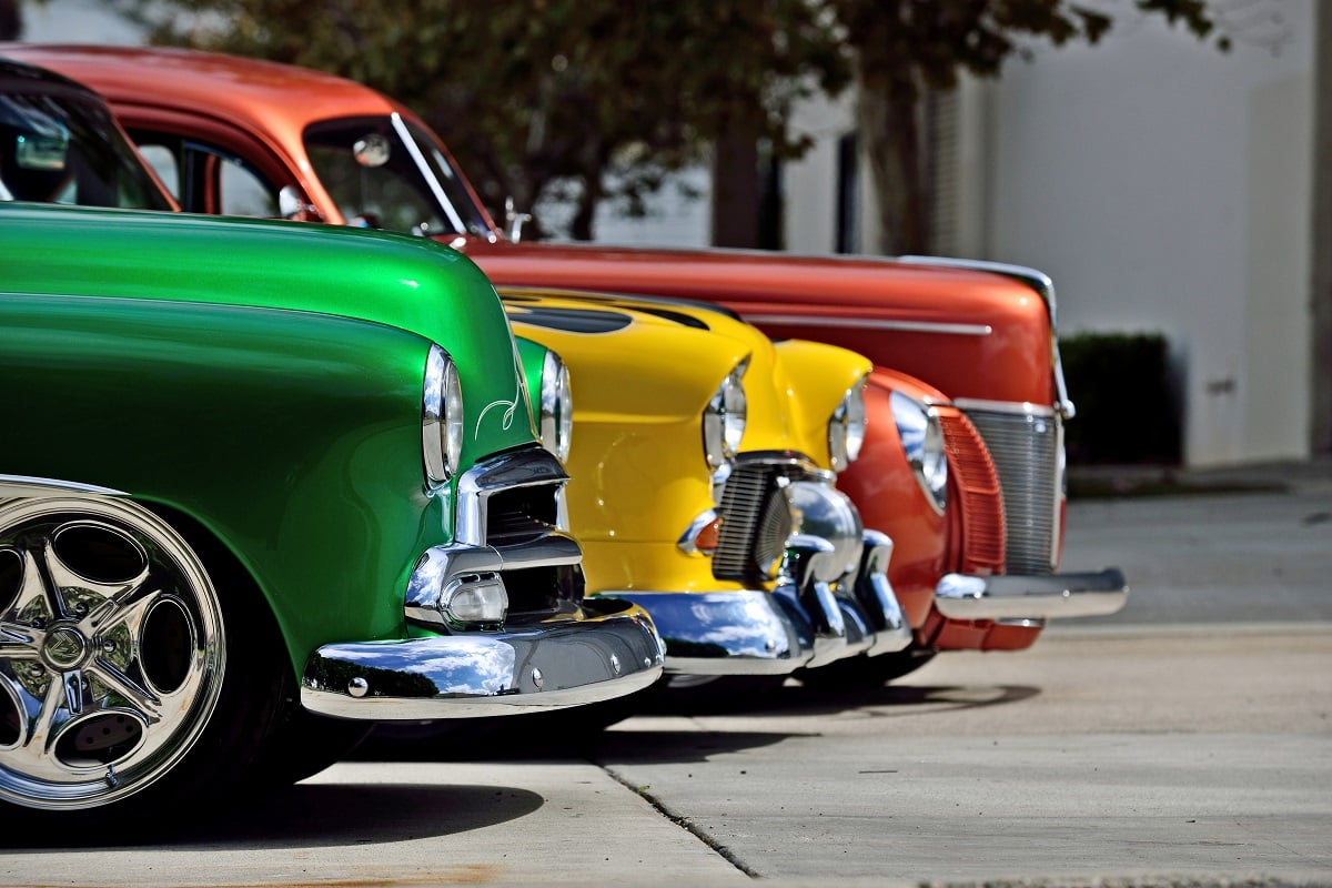 Classic cars in vibrant colors are displayed at a car show